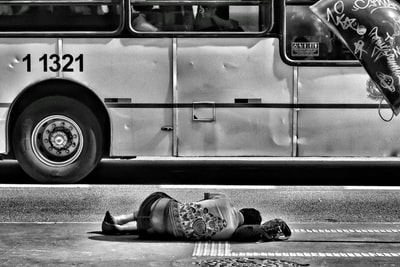躺在公共汽车附近地面上的人的灰度照片